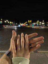 Midsection of woman hand on illuminated street at night