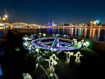 Illuminated ferris wheel in city against clear sky at night