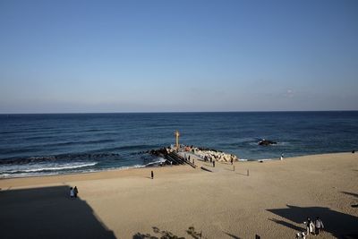 Scenic view of beach with people against clear sky