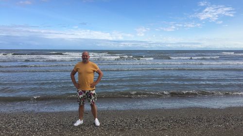 Portrait of man standing at beach against sky