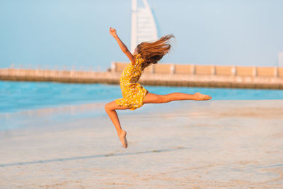 Woman jumping on beach against sky