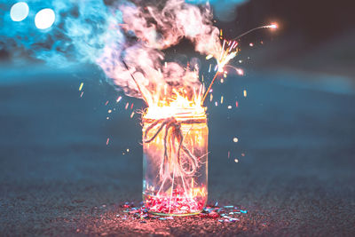 Close-up of sparklers burning in jar in road at night