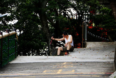 Full length of shirtless man sitting on street