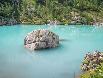 Rock formation by lake against trees