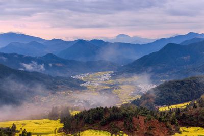 Scenic view of mountains against cloudy sky at sunset