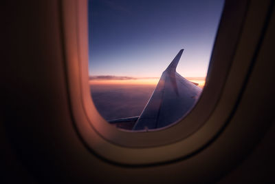 Airplane flying in sky seen through glass window