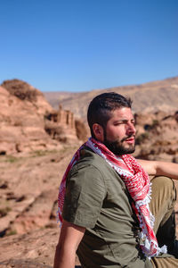 Young man standing in desert against clear sky