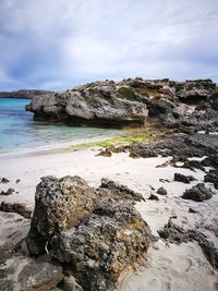 Scenic view of rocks on shore against sky