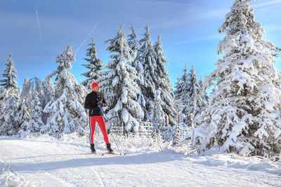 Man skiing on snow covered field against trees
