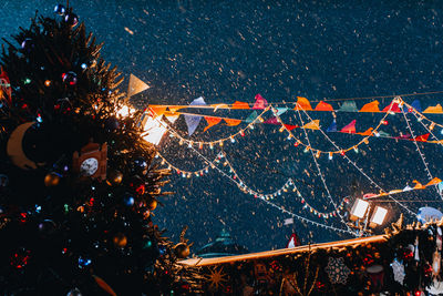 Christmas tree and flying snow in the evening light in festive magic new year atmosphere