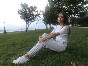 Beautiful young woman sitting on field