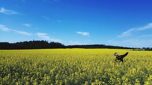 Man standing on field against blue sky