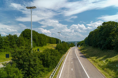 Road amidst plants and trees against sky