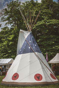 Old-fashioned tent on grassy field against trees at event