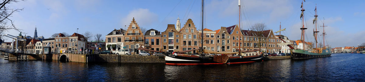 Panoramic view of boats moored in river by buildings in city