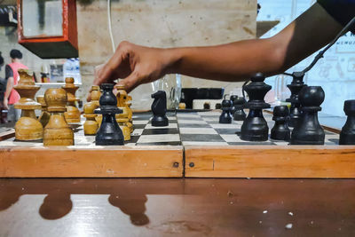 Midsection of person with chess pieces on table