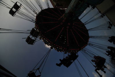 Low angle view of silhouette chain swing ride against sky