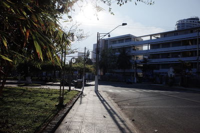 Road by buildings in city against sky