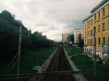 Railroad tracks in city against sky