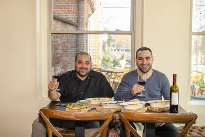 Two proud business owners sit together at a restaurant table with wine