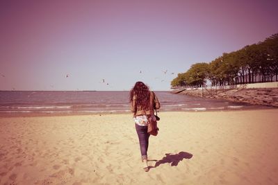 Woman on beach against clear sky