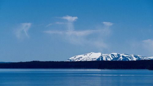 Scenic view of lake by snowcapped mountain against sky