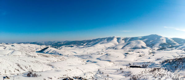 Scenic view of snowcapped mountains against blue sky