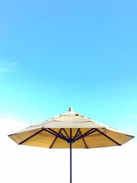 Low angle view of parasol against clear blue sky