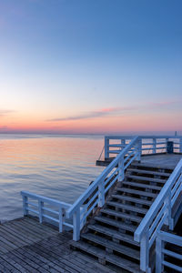 Empty pier on sea against sky during sunset