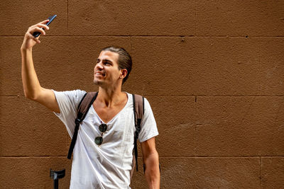 Young man with crutches taking a selfie with his mobile in the street