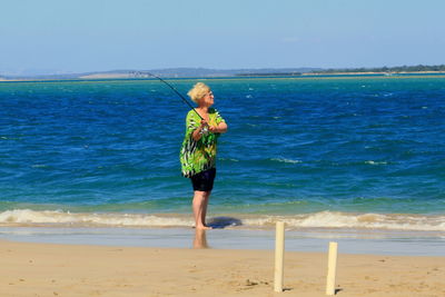 Side view of woman fishing on beach