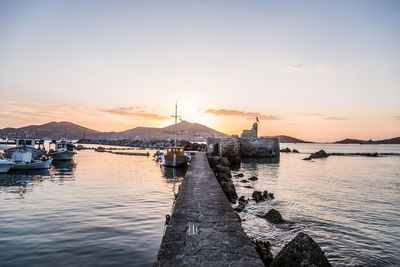 Sailboats moored on sea against sky during sunset