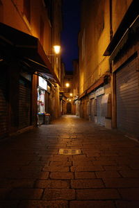 Empty narrow alley along buildings at night