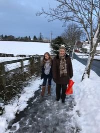 Full length portrait of young woman standing on snow covered landscape