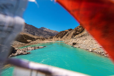 Scenic view of sea by mountain against sky
