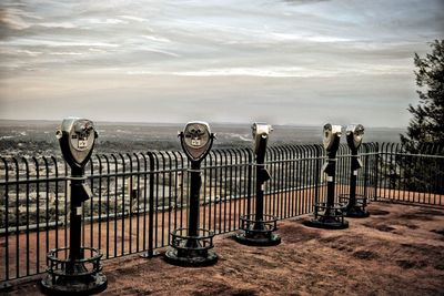 Bicycles on railing by sea against sky