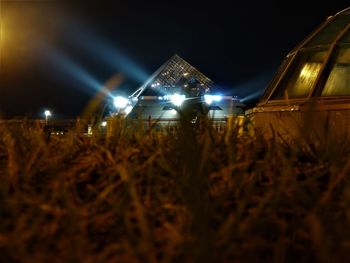 Illuminated field against sky at night