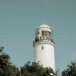 Lighthouse by sea against clear sky