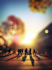 Tilt-shift image of silhouette people walking on city street during sunset