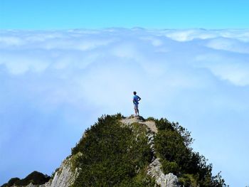 Man standing on rock against sky