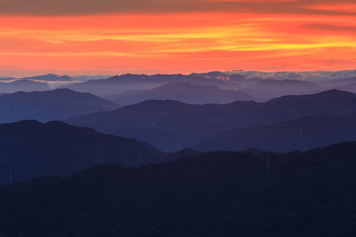 Scenic view of silhouette mountains against orange sky