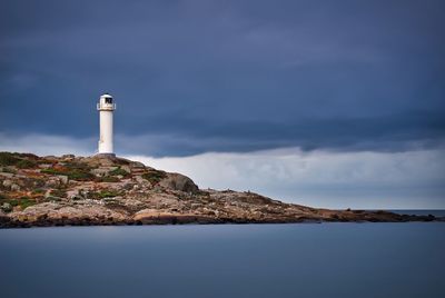 Lighthouse by sea against sky