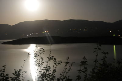 Scenic view of lake by silhouette mountains against sky