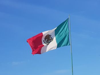 Low angle view of mexican flag against blue sky