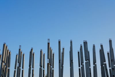 Low angle view of wooden posts against clear blue sky