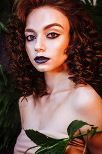 Portrait of beautiful redhead woman wearing make-up against plants