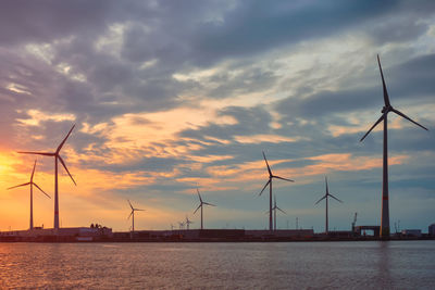 Wind turbines in antwerp port on sunset.