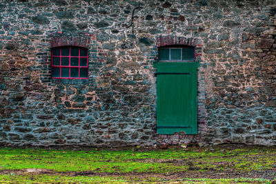 Farm house facade with red window and green door