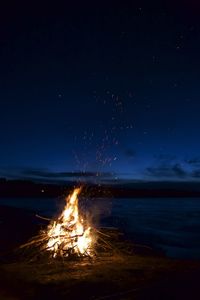 Bonfire on beach against sky at night