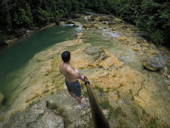 High angle view of man standing on rock by river